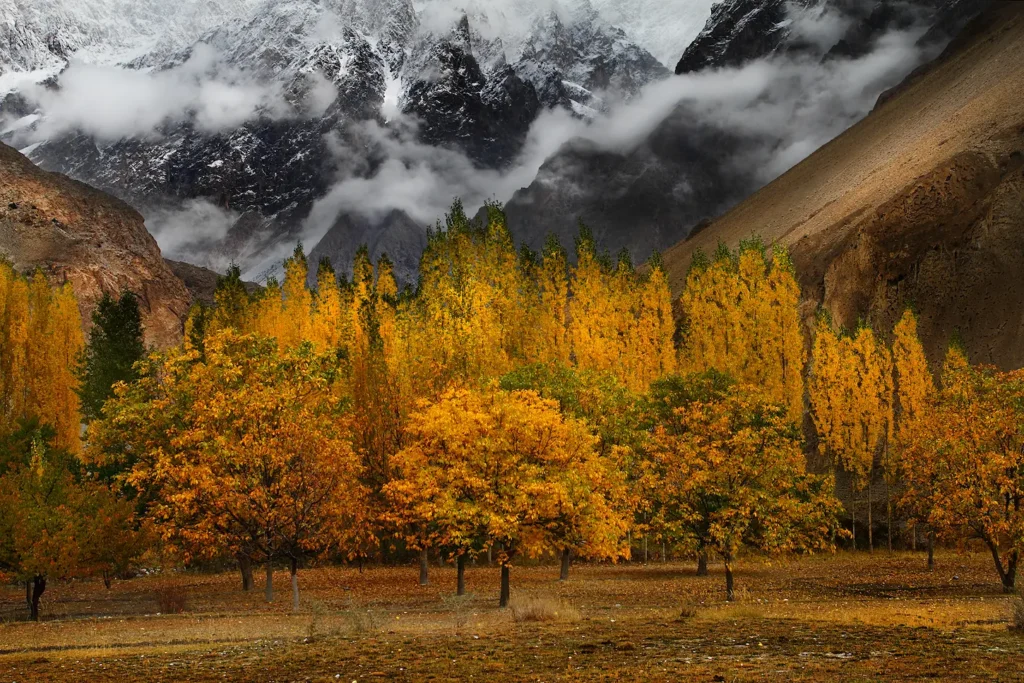 Hunza Valley road with a white jeep beside a turquoise lake and rocky peaks