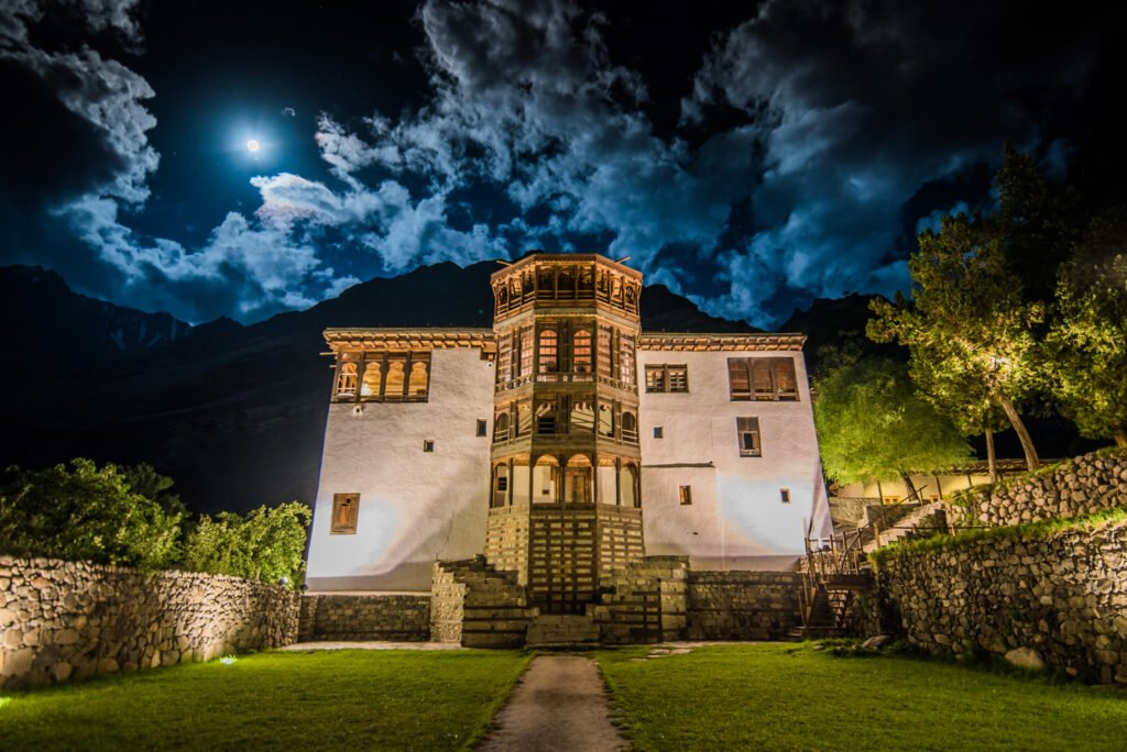Sunlit upper hall of Khaplu Palace with carved wooden arches and valley views
