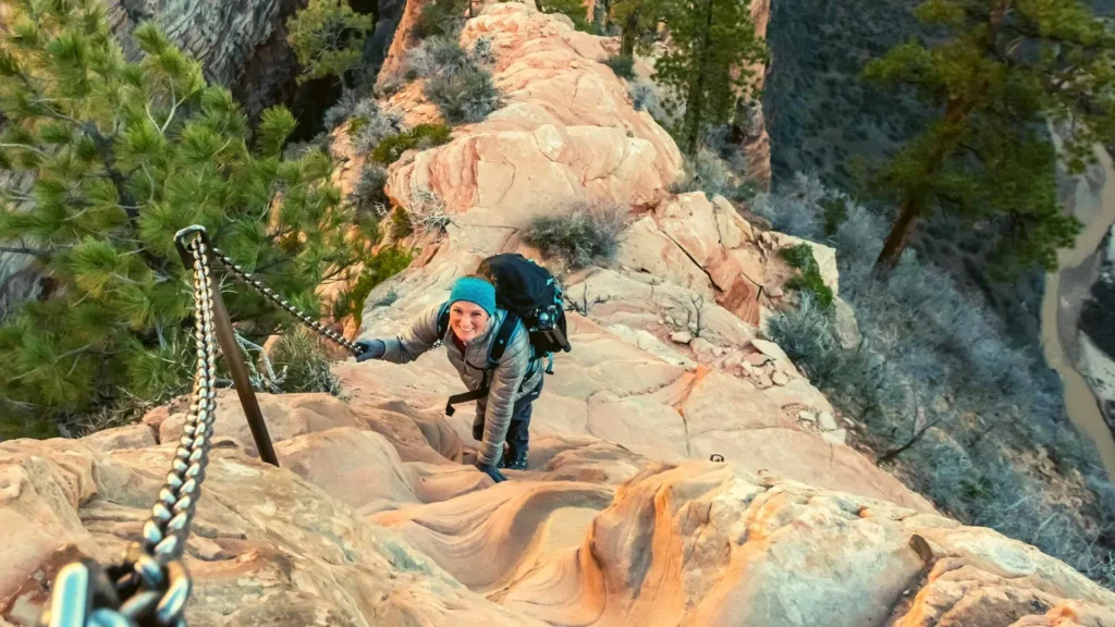 Hiker with a backpack sitting on a rock and wiping her brow, fear on steep hiking trails
